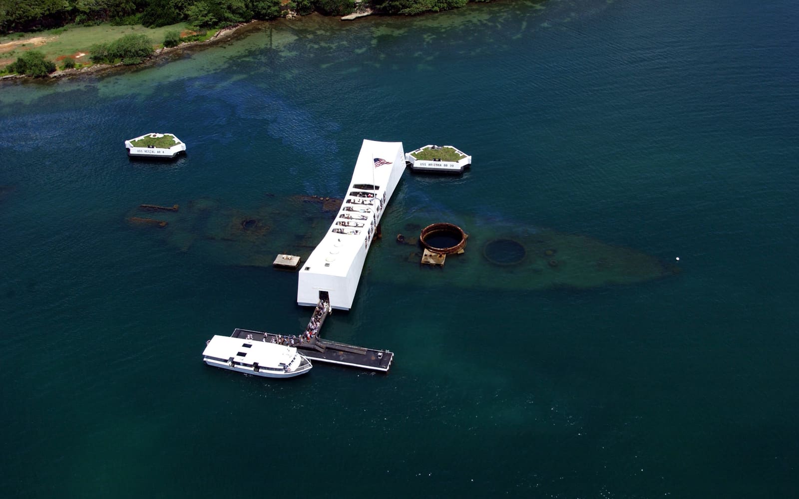 Aerial view of the white USS Arizona Memorial spanning the sunken battleship USS Arizona in Pearl Harbor, Hawaii