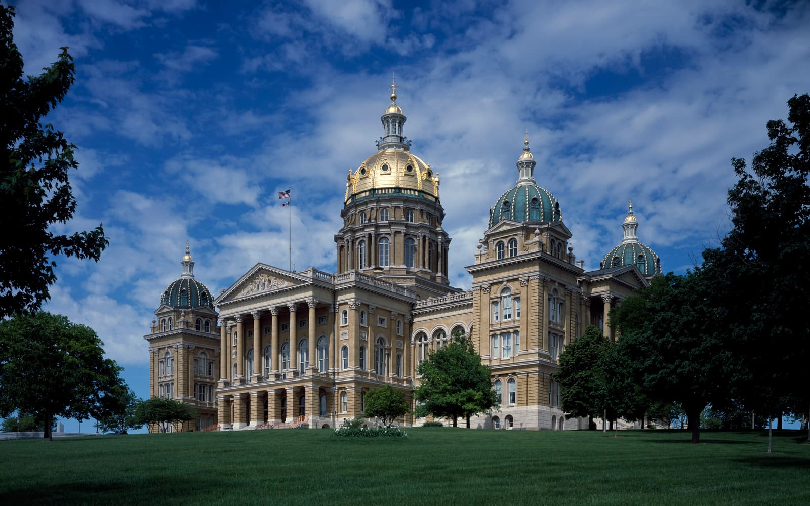 The Iowa State Capitol in Des Moines with its gold-leafed central dome and four corner domes under a blue sky