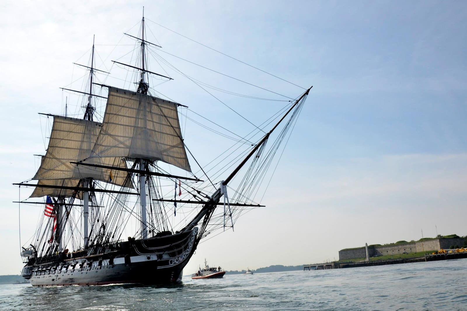 USS Constitution under full sail in Boston Harbor with Fort Independence at Castle Island in the background